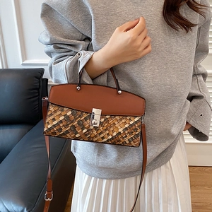Brown woven crossbody bag with leather flap shown on a model in a casual indoor setting