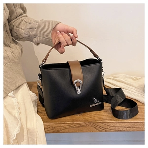 Close-up of black and brown leather bucket bag with metallic logo and textured strap