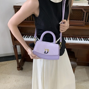 Detail of light purple snake-embossed box bag with a golden D-logo and shoulder strap