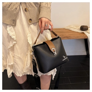 Detail of black pebbled leather bucket bag with brown handle and kangaroo logo metal tag