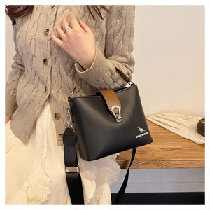Detail of black leather bucket bag with brown handle and adjustable wide nylon shoulder strap