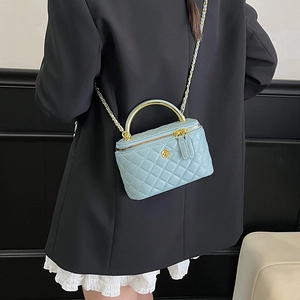 Mini sac boîte bleu clair matelassé avec poignée dorée et bandoulière porté par mannequin