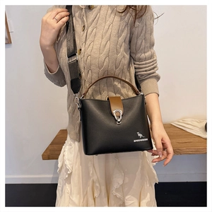 Detail of black leather bucket bag featuring a silver kangaroo logo and wide woven strap