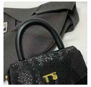 Detailed close-up of snake-embossed black leather handbag with gold T5 logo hardware