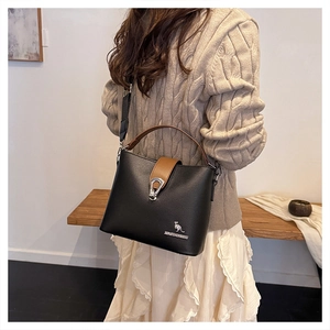 Detail of a chic bucket bag showing the black pebble leather and brown trim with metal logo