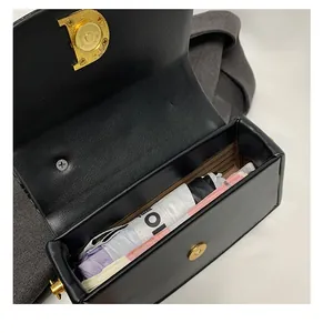 Detail view of black leather box bag interior with gold D-shaped metal buckle hardware