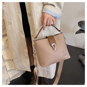 Close-up of beige textured leather bucket bag with silver buckle and woven shoulder strap