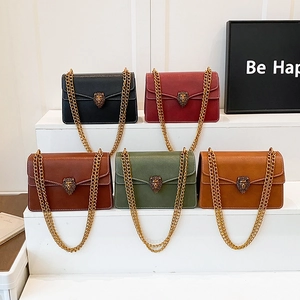 Five elegant leather chain shoulder bags with lion head buckles on a white display stand