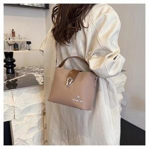 Close-up of beige bucket bag featuring a silver kangaroo icon and refined texture