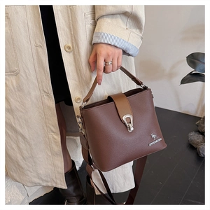 Detail of a brown lychee-patterned bucket bag with gold kangaroo emblem and handle