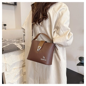 Detail of dark brown leather bucket bag with metal kangaroo logo and shoulder strap
