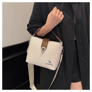 Detail of cream grained leather bucket bag with brown handle and kangaroo logo metal clasp