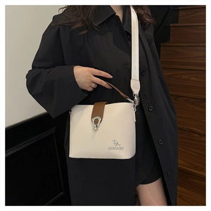 Detail of cream leather bucket bag with silver kangaroo logo and wide fabric strap