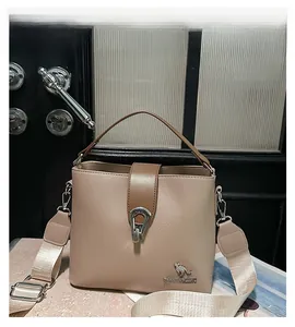 Detail view of beige bucket bag showing metal horseshoe buckle and kangaroo logo