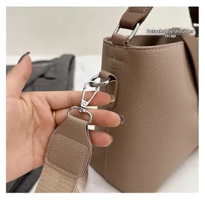 Detail of detachable shoulder strap with silver hook on taupe leather bucket bag
