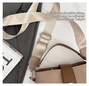 Detail of adjustable woven shoulder strap on a taupe pebble leather bucket bag