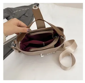 Detail of a brown bucket bag with three internal compartments and a burgundy lining