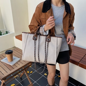 Chic beige canvas tote bag with brown leather trim and chain strap for autumn fashion