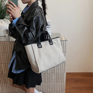 Chic beige canvas tote bag with black leather trim and silver chain shoulder strap for women
