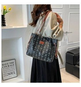 Detail of printed tote bag with bear patterns, brown leather straps and metal hardware