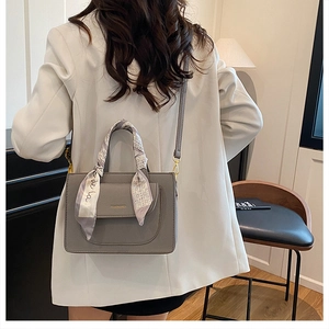 Detail of grey leather tote bag with silk scarf handle and elegant gold hardware