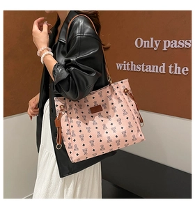 Close-up of pink tote bag featuring black bear prints and textured leather finish