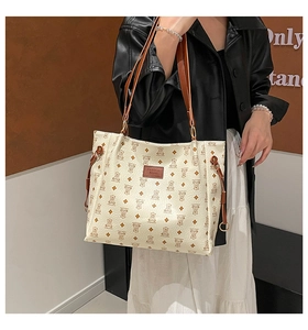 Detail of a large cream tote bag featuring retro bear patterns and a brown fashion tag