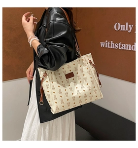 Dettaglio borsa tote color crema con orsetti e cinturini in pelle indossata da modella