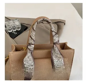 Detail of premium textured leather handbag with elegant silk scarf wrapped around handle