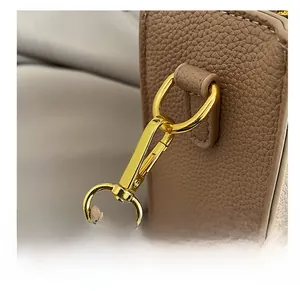 Detailed close-up of brown litchi leather bag with gold metal hook and precise stitching
