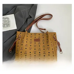 Close-up of yellow tote bag with bear print, brown strap, and fashion leather patch