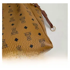 Close-up of yellow lychee-textured leather tote with bear prints and metal ring detail