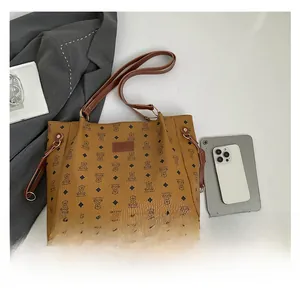 Detail of brown tote bag with bear pattern, leather tag and dual shoulder straps