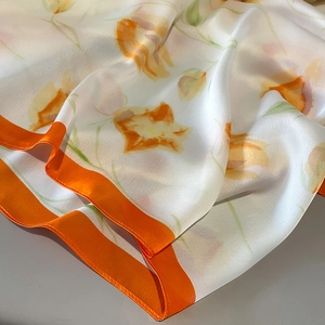 Detailed view of the silk satin tulip print scarf with vibrant orange contrast borders