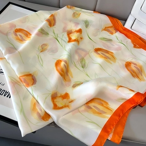 Detailed shot of tulip print silk scarf with orange borders on a leather bench