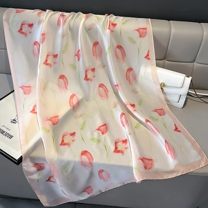 Detailed close-up of a floral silk scarf with red tulips on a textured sofa
