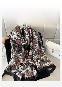 Detail of silk-feel scarf featuring intricate paisley patterns and delicate black hem edge