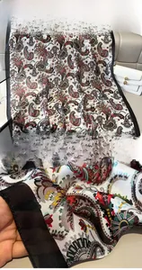Detail of bohemian paisley silk scarf featuring red patterns and fine black edge stitching