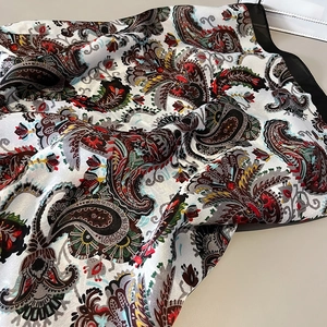 Detail of silk-like satin shawl with colorful paisley print and black border edges