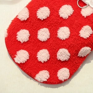 Detail of red plush pet vest featuring pink polka dots, white lace, and metal D-ring buckle
