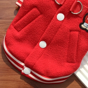 Close-up of red fleece dog jacket with metal D-ring and striped ribbed hem detail