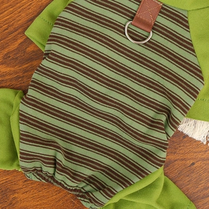 Detail of striped dog jumpsuit with green and brown patterns and metal D-ring for leash