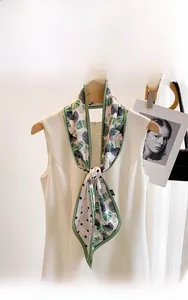 Detail of silk scarf with green ginkgo leaves and black polka dot knot pattern