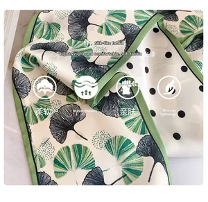 Detailed macro of soft silk satin scarf with green ginkgo leaves and black polka dots