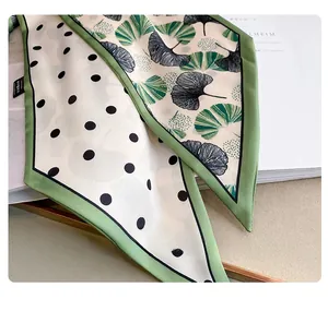Detailed shot of silk scarf featuring polka dots and green ginkgo leaf patterns