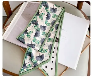 Close-up of silk twilly scarf with green ginkgo leaves and polka dot patterns
