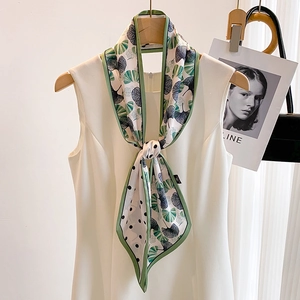 Green ginkgo leaf and polka dot print long silk scarf styled on a white dress