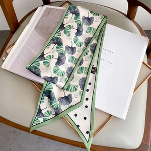 Polka dot silk twilly scarf with green ginkgo leaves on a beige background