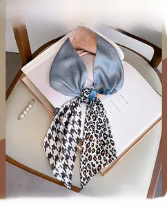 Blue-gray gradient silk scarf with star patterns and pearl clip on a white magazine