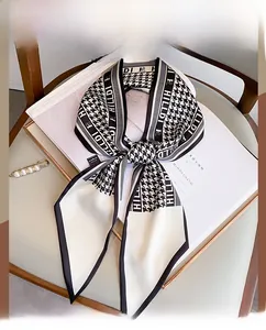 Detail of elegant black and white houndstooth silk scarf with HILLDI text on a magazine